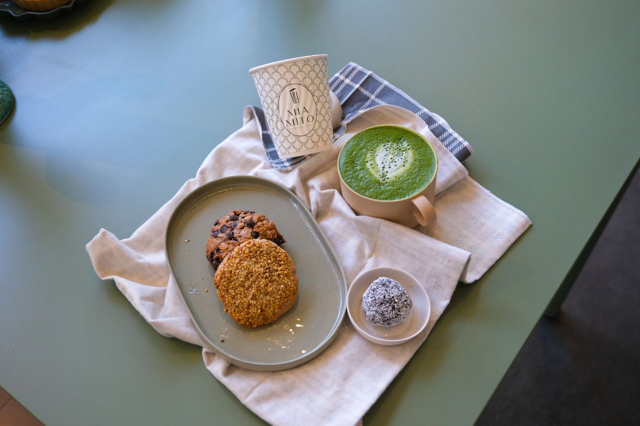 A warm photo of a matcha latte with cookies and a dessert in a cozy Ankara cafe.
