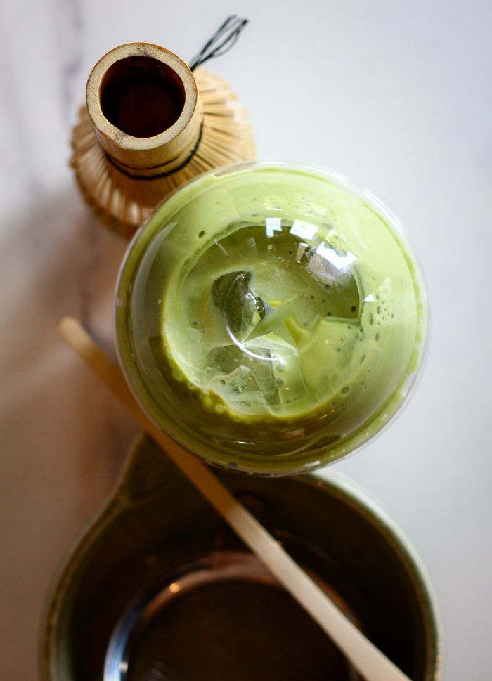 Close-up of traditional matcha tea preparation with bamboo whisk and matcha bowl.
